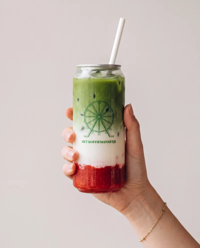 Hand holding a glass can of strawberry matcha with the Het Koffiemannetje logo